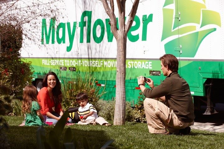 Family sitting in a front yard next to a moving truck