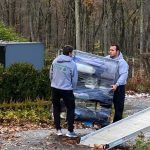 Two movers carry a dolly of items on a ramp for a move in Hartford.