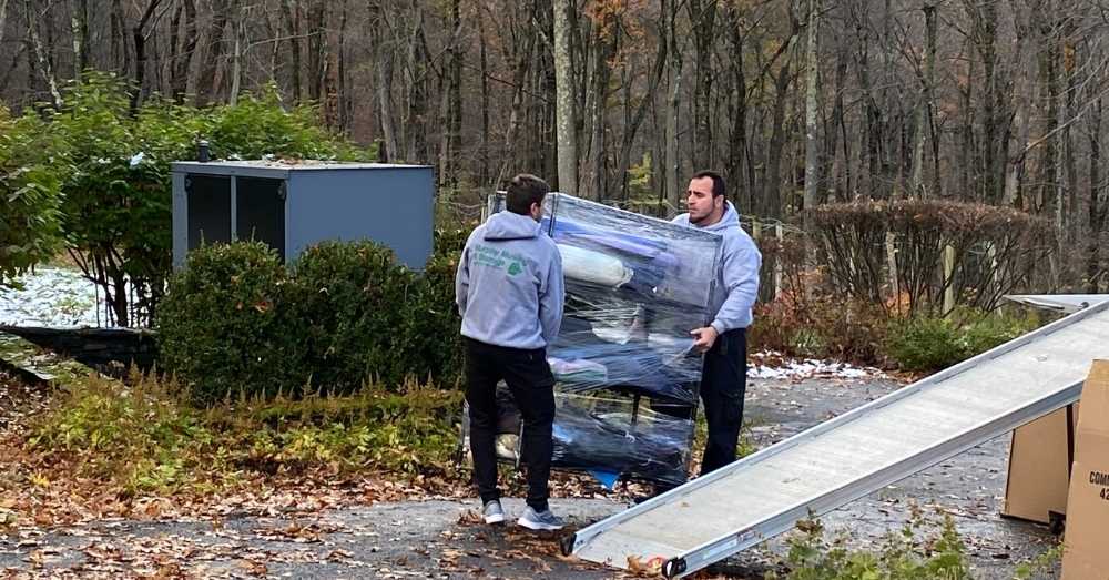Two movers carry a dolly of items on a ramp for a move in Hartford.