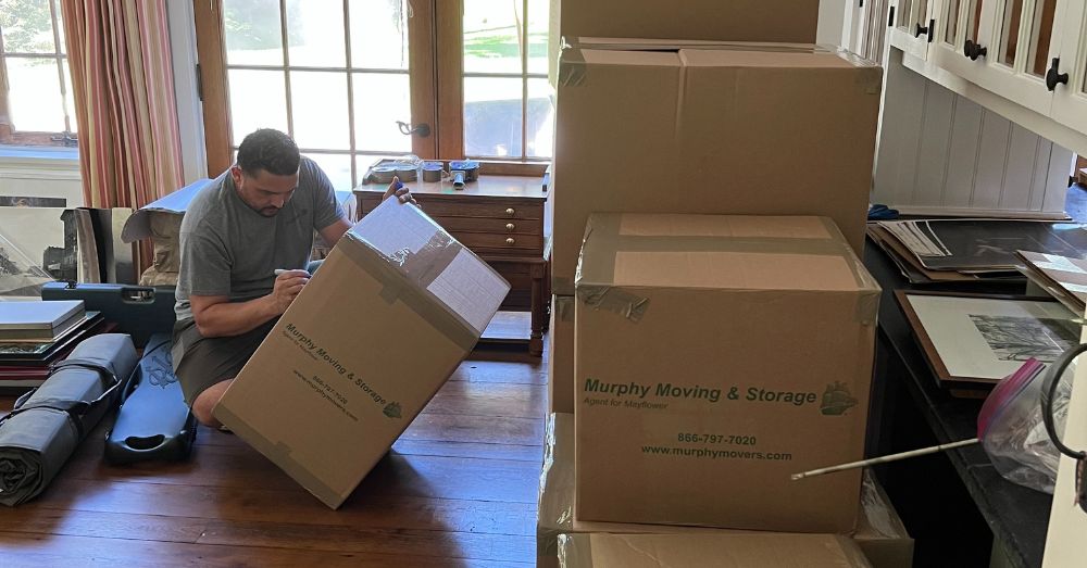 A mover kneels to label a Murphy Moving & Storage box.