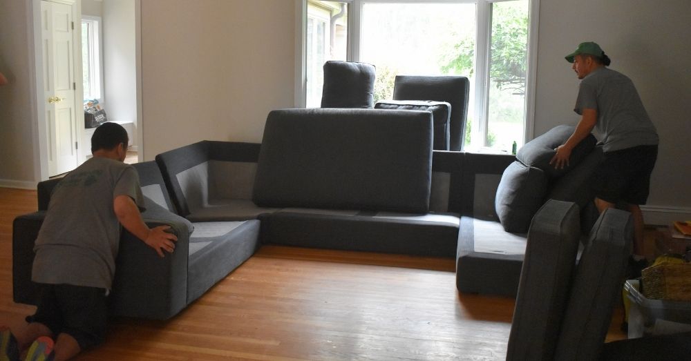 Two movers are arranging a sectional sofa for a move in Hartford.