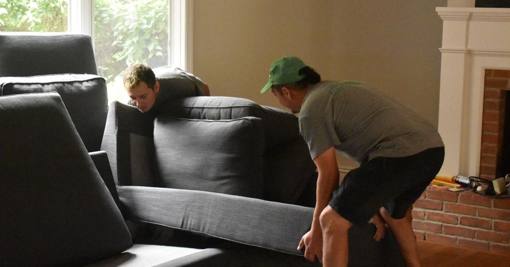 Two people struggling to move a large sofa