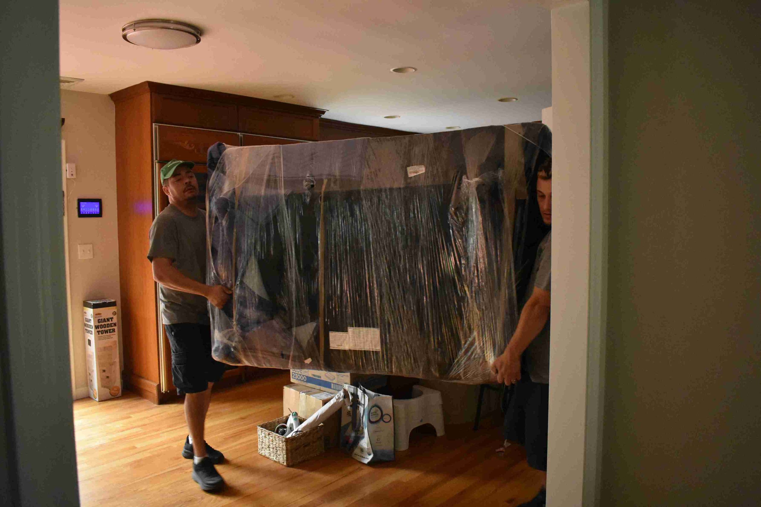 two persons carrying the item into the moving truck