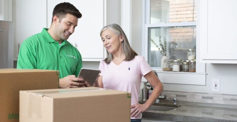 Homeowner with Packer showing list of moving boxes