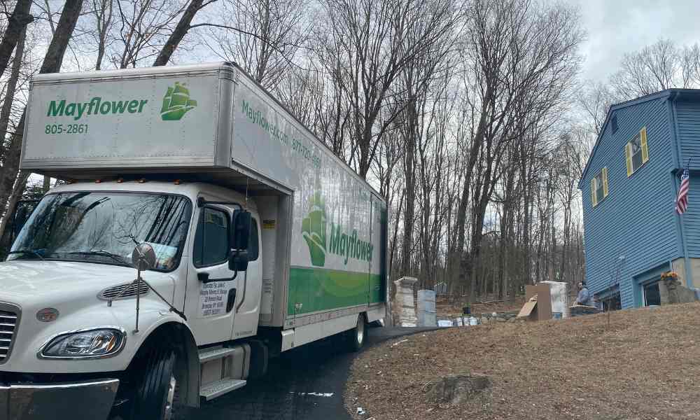 A white Mayflower moving truck parked on a sloped residential driveway