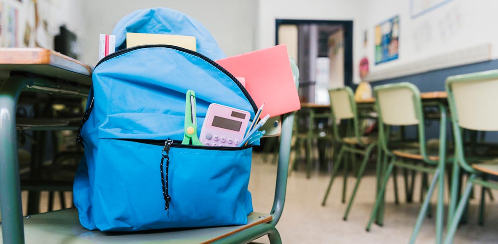 school backpack with supplies on top of a chair