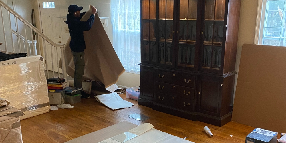 a person carefully lifting and wrapping a large piece of furniture