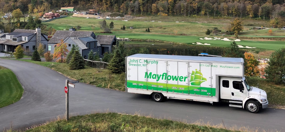 Mayflower moving truck driving along a paved road
