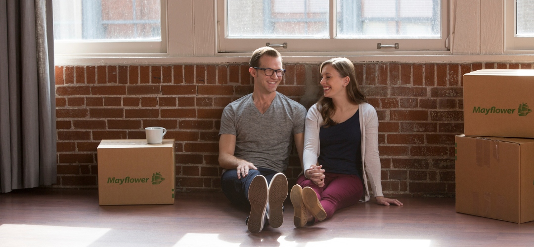 smiling couple sits on the floor of a new apartment