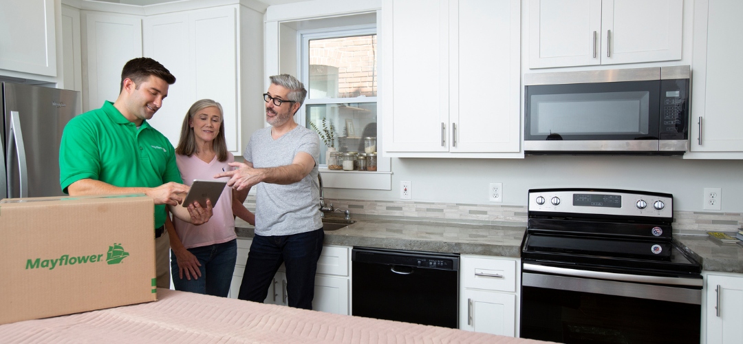 a mover in a green shirt shows a tablet to a couple