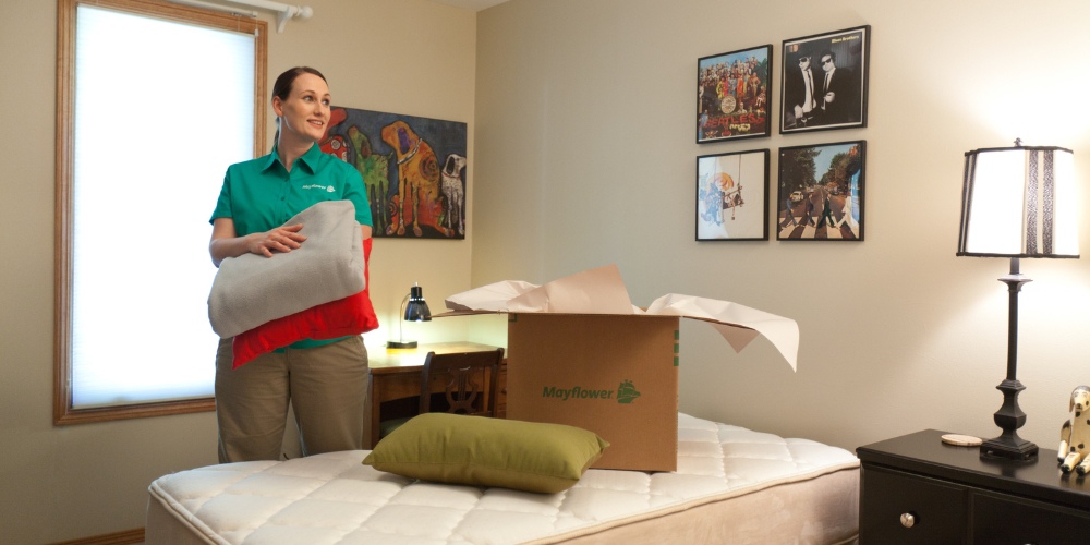 A woman wearing a green Mayflower shirt holding a folded gray blanket
