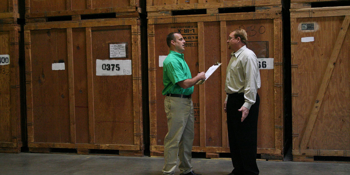 Mover and client talking in front of large moving boxes