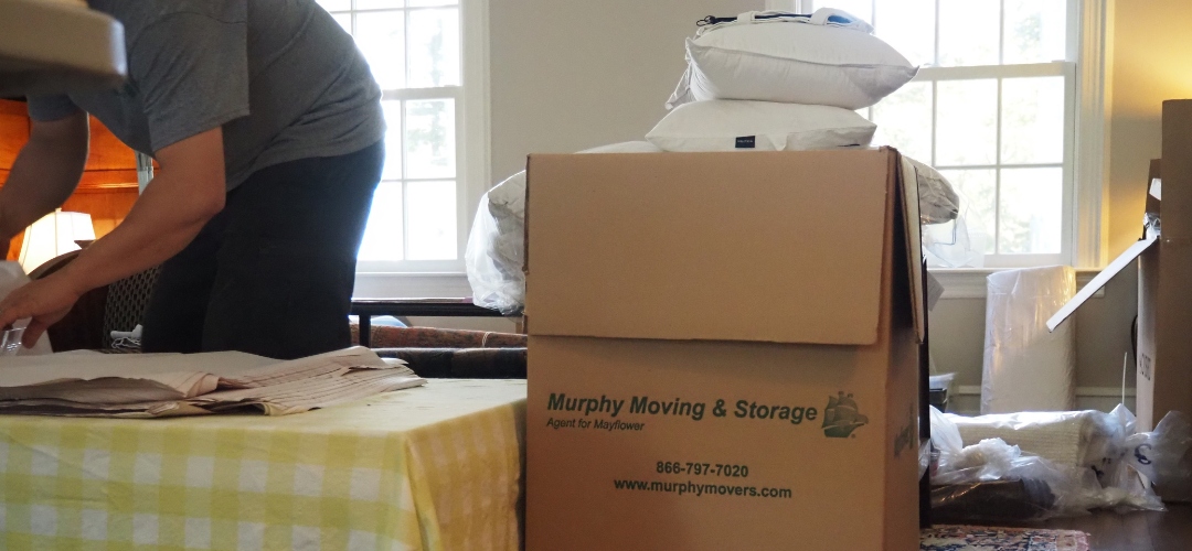 A mover packs packing paper next to a large cardboard box