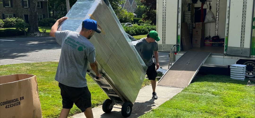 Two movers unloading a large, wrapped item
