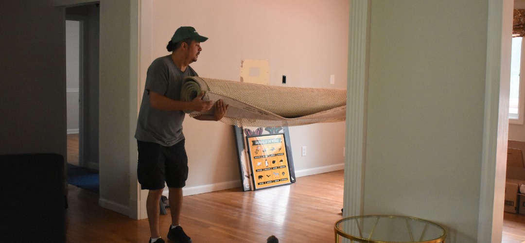 a man carrying a large, rolled-up rug