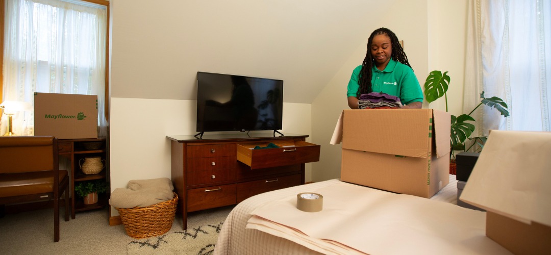 a professional mover packing clothes into a cardboard box