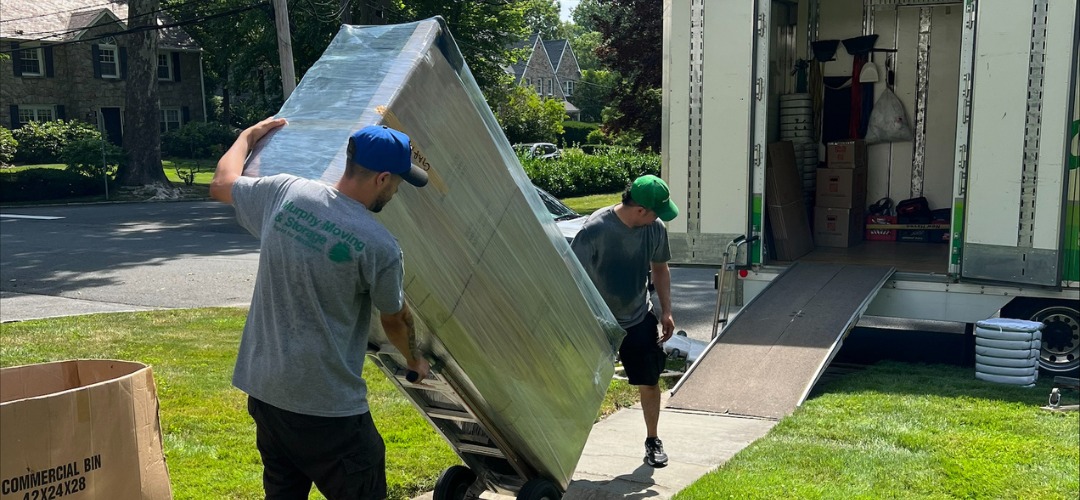 Two workers loading a wrapped piece of furniture