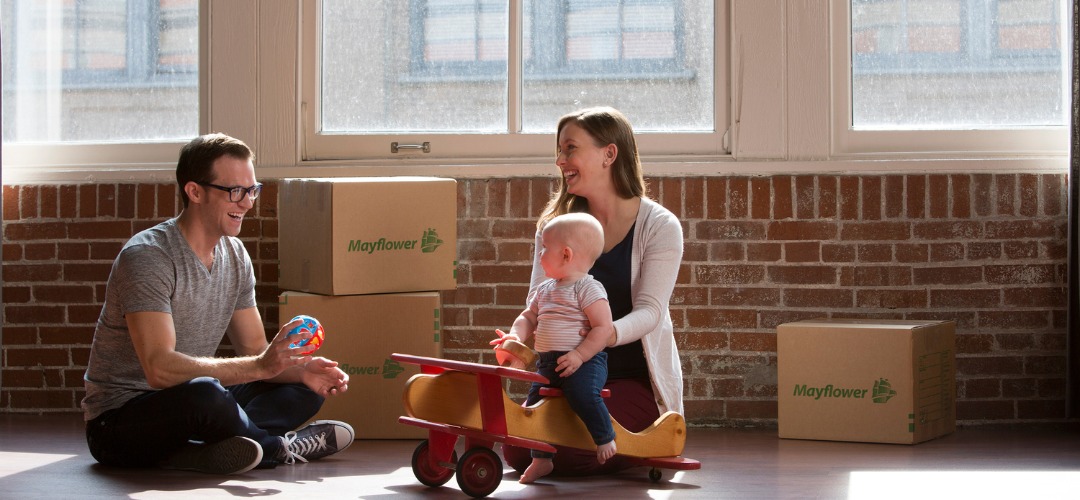 Parents with a baby and moving boxes in a room